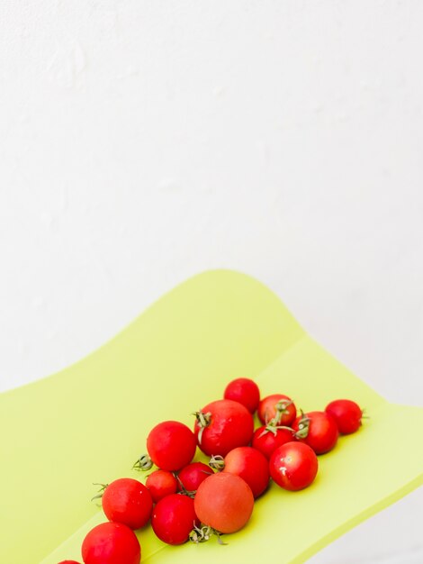 Tomates de cereza rojos frescos en tajadera contra el fondo blanco