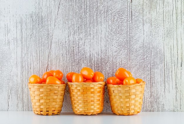 Foto gratuita tomates en cestas en la mesa blanca y sucia. vista lateral.