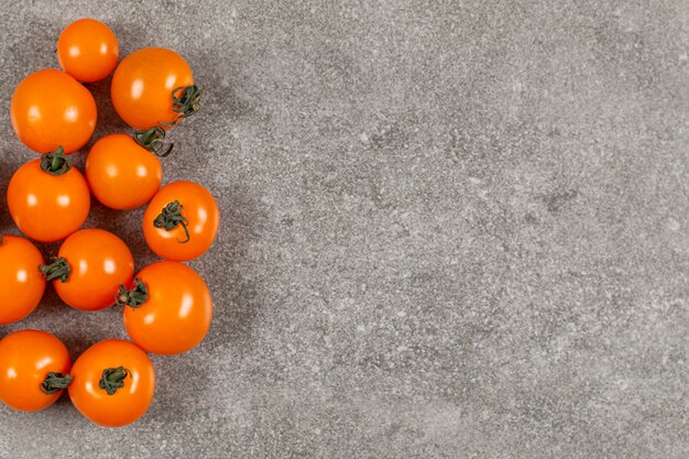 Tomates cherry amarillos sobre gris.