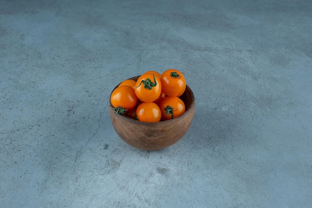 Tomates cherry amarillos en una taza en azul.