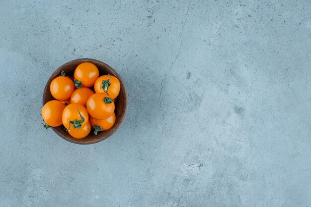 Tomates cherry amarillos en una taza de madera.