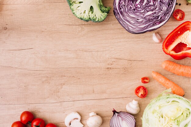 Tomates cherry; brócoli; repollo; Zanahoria; cebolla; pimiento rojo en mesa de madera