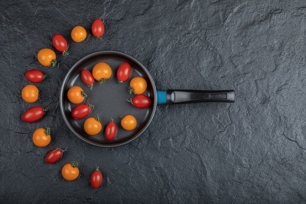 Tomates cherry de colores orgánicos en la sartén sobre fondo negro. Foto de alta calidad