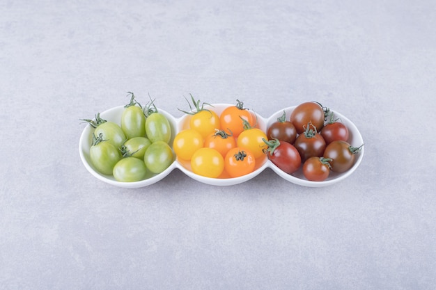 Tomates cherry coloridos en tazones de fuente blancos.