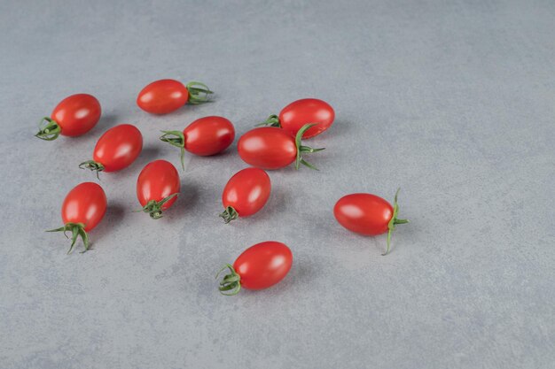 Tomates cherry rojos aislados en mesa gris.