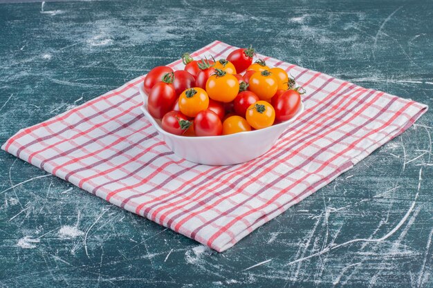 Tomates cherry rojos y amarillos aislados en superficie azul.