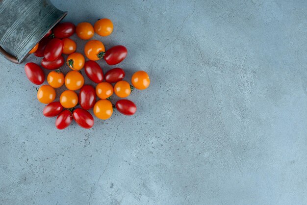 Tomates cherry rojos y amarillos sobre gris.