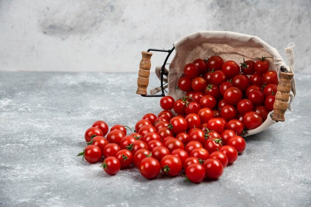 Tomates cherry rojos en una canasta sobre mesa de mármol.