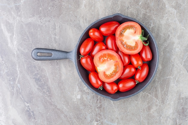 Tomates cherry rojos en una sartén negra.