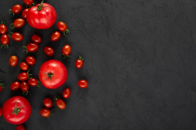 Tomates cherry rojos y tomates habituales en suelo gris