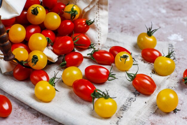 Tomates cherry de varios colores, tomates cherry amarillos y rojos en una cesta sobre fondo claro