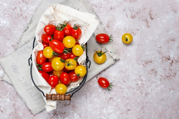 Tomates cherry de varios colores, tomates cherry amarillos y rojos en una cesta sobre fondo claro