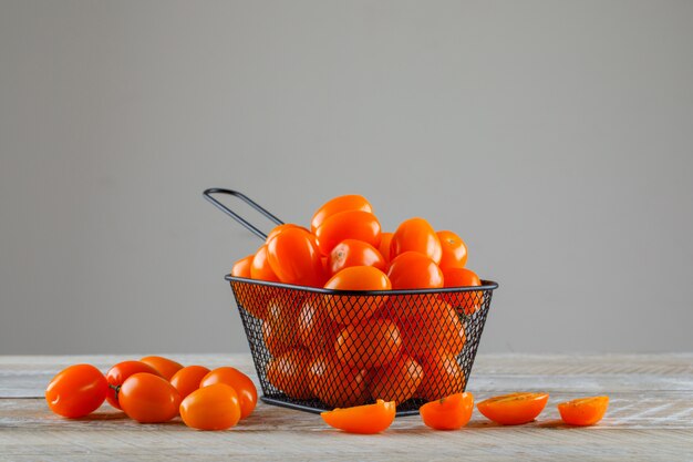 Tomates en un colador en mesa de madera y gris. vista lateral.