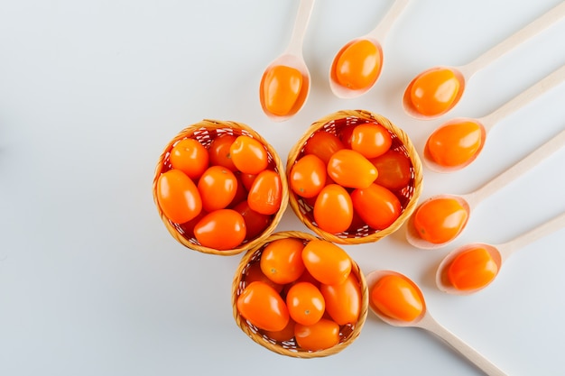 Tomates en cucharas de madera y cestas. aplanada