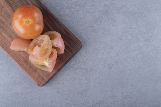 Tomates con dientes en la tabla de cortar, sobre el fondo de mármol.