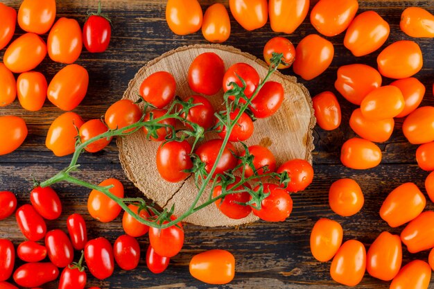 Tomates dispersos en tabla de cortar y madera. aplanada