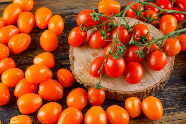 Tomates dispersos en tabla de cortar y madera. Vista de ángulo alto.