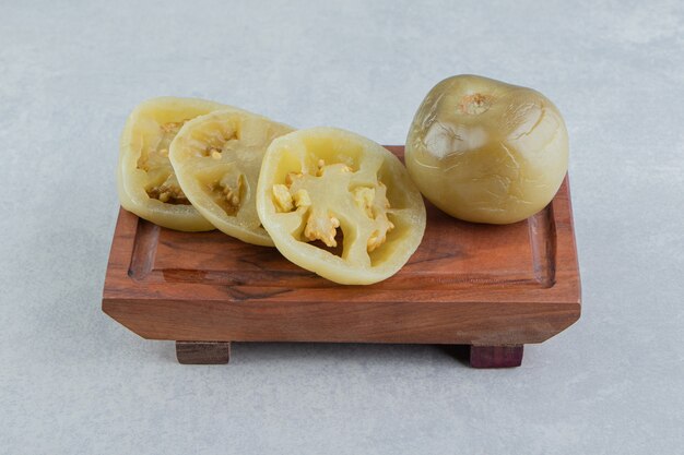 Tomates enteros y en rodajas en el plato de madera