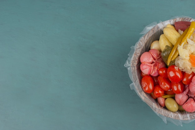 Tomates en escabeche, aceitunas, ajo, repollo, pepinos en balde de madera.