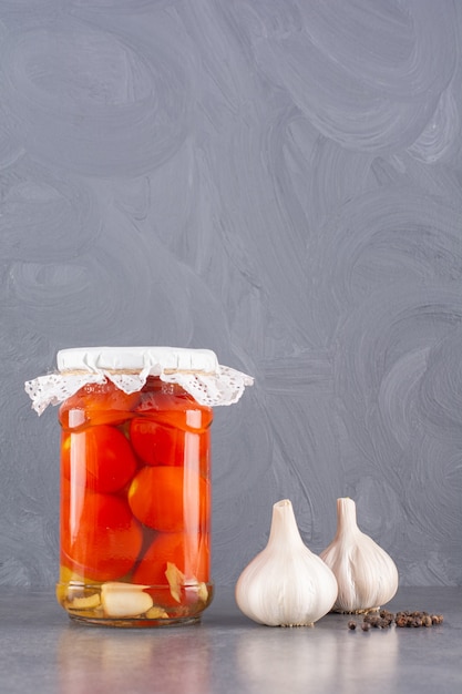 Tomates en escabeche con ajo fresco colocados sobre una mesa de piedra.