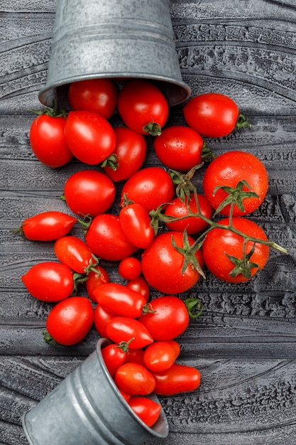 Tomates esparcidos de mini cubos planos sobre una pared de madera gris