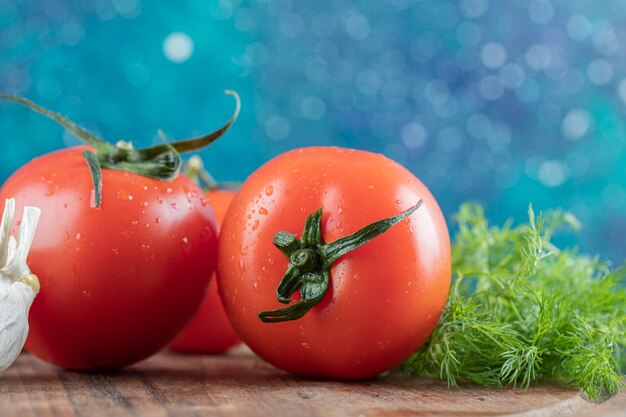 Tomates frescos con ajo sobre una tabla de madera.