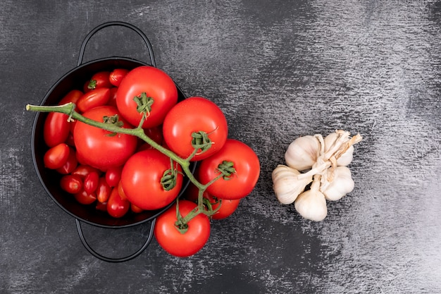 Foto gratuita tomates frescos en una olla y ajos