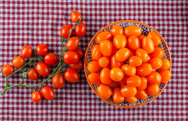 Tomates frescos en un plato sobre un paño de picnic. aplanada