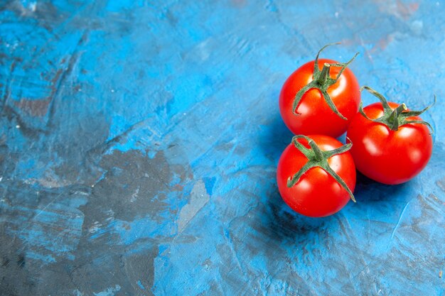 Tomates frescos de vista frontal en la mesa azul