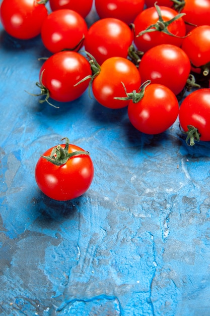 Tomates frescos de vista frontal en la mesa azul