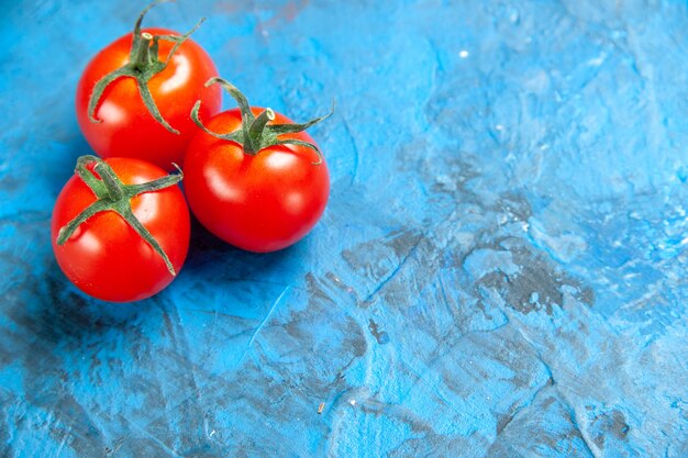 Tomates frescos de vista frontal en la mesa azul