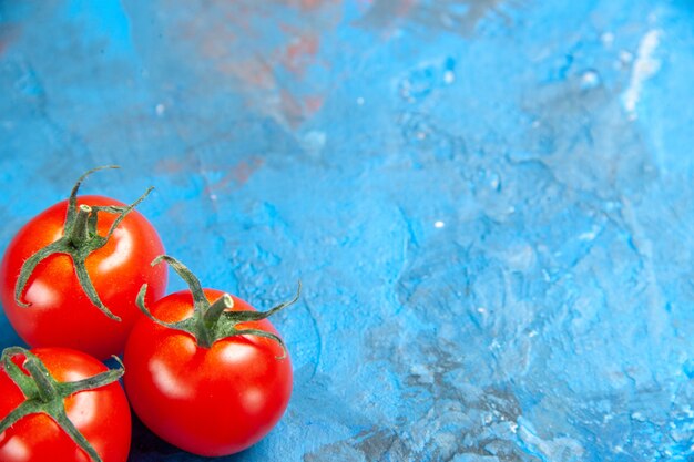 Tomates frescos de vista frontal en la mesa azul