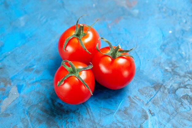 Tomates frescos de vista frontal en la mesa azul