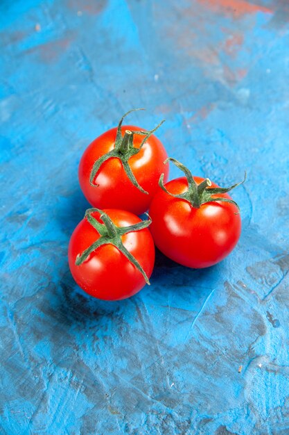 Tomates frescos de vista frontal en la mesa azul