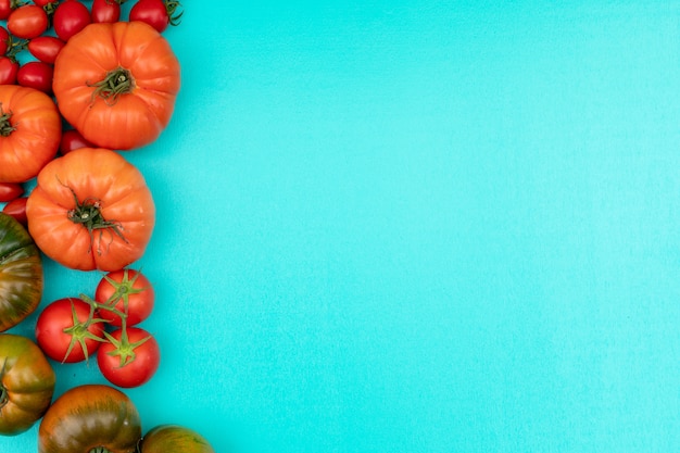 Tomates a la izquierda del marco con espacio de copia en superficie azul claro