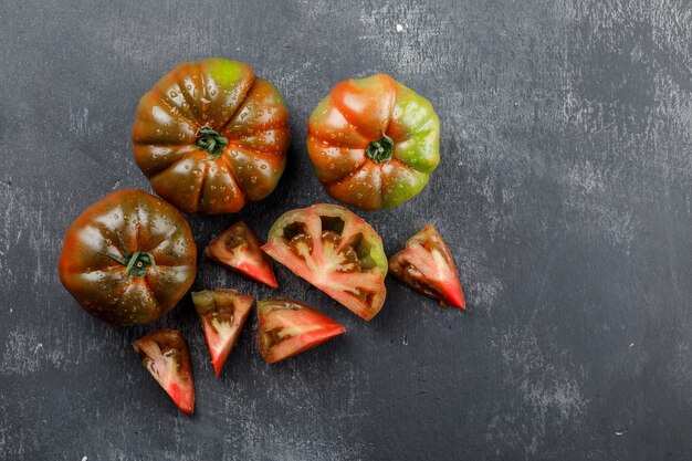 Tomates Kumato con rodajas vista superior en una pared gris sucio