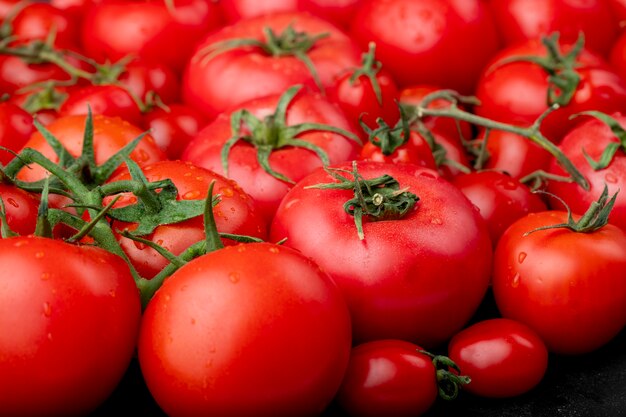 Tomates maduros con gotas de agua como vista lateral de fondo