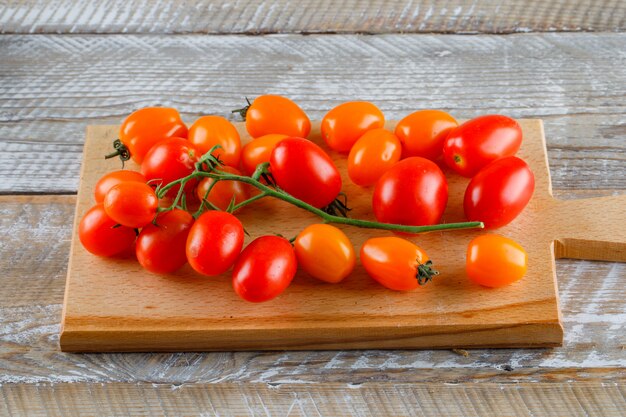 Tomates maduros en madera y tabla de cortar.