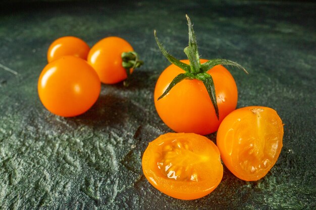 Tomates naranja vista frontal sobre superficie oscura