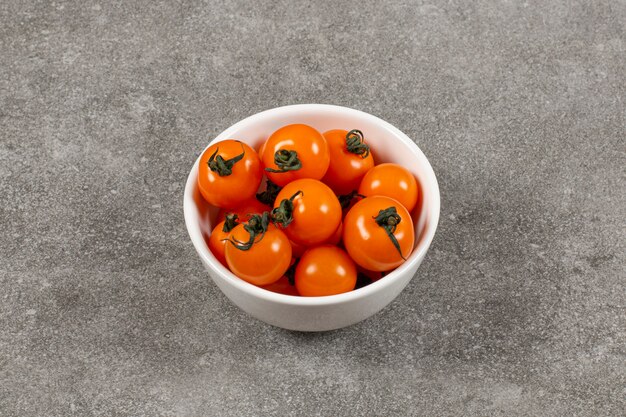 Tomates orgánicos en el bol, sobre el mármol.