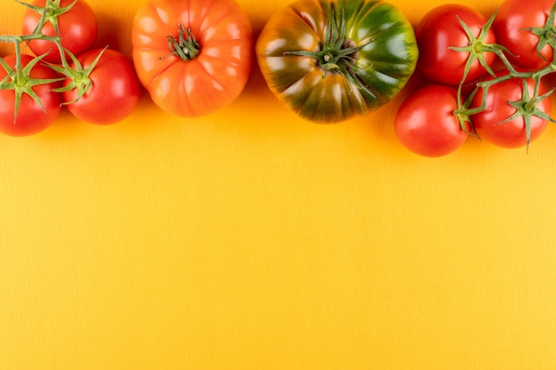 Foto gratuita tomates en la parte superior del marco sobre superficie amarilla