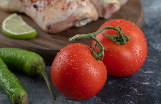 Tomates y pimientos orgánicos frescos con muslos de pollo crudo