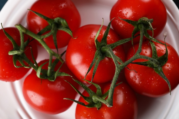 Tomates rojos con agua rocía sobre ellos en un plato blanco.