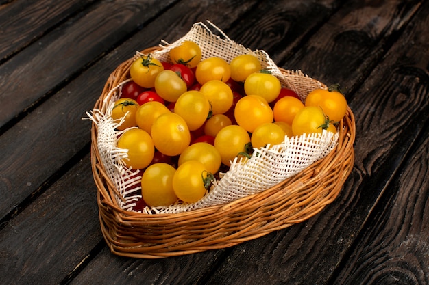 Tomates rojos amarillos vitamina fresca madura rica dentro de ataúd marrón sobre el escritorio de madera rústica