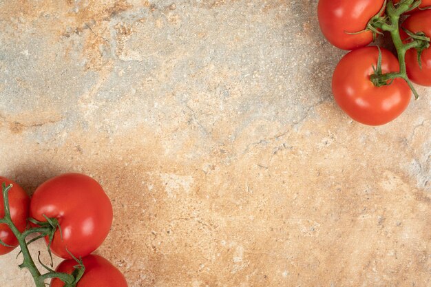 Tomates rojos cereza en una rama sobre la superficie de mármol.