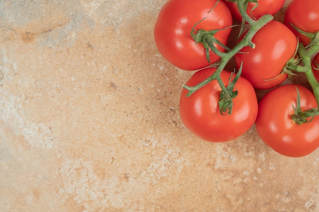 Tomates rojos cereza en una rama sobre la superficie de mármol