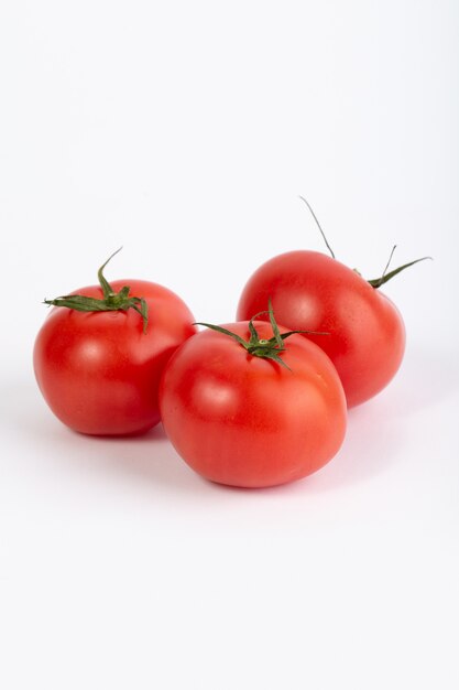 Tomates rojos frescos maduros suaves sobre fondo blanco.