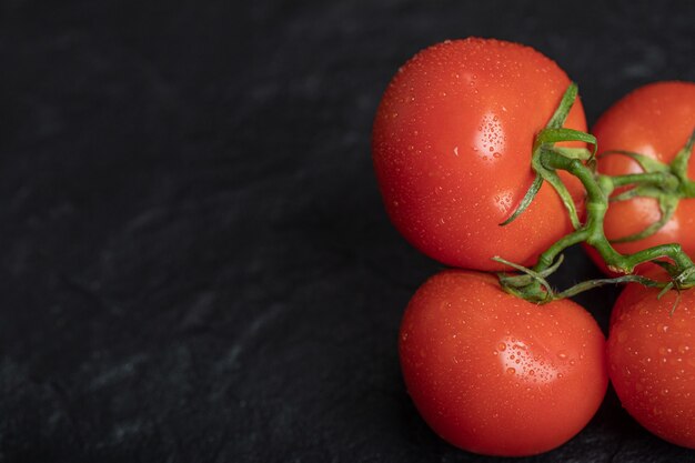 Tomates rojos frescos sobre superficie oscura