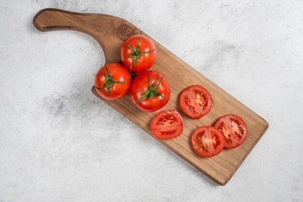 Tomates rojos frescos sobre una tabla de cortar de madera