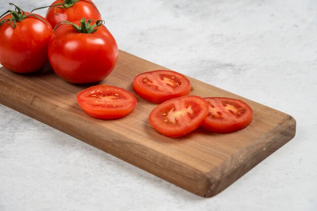 Tomates rojos frescos sobre una tabla de cortar de madera